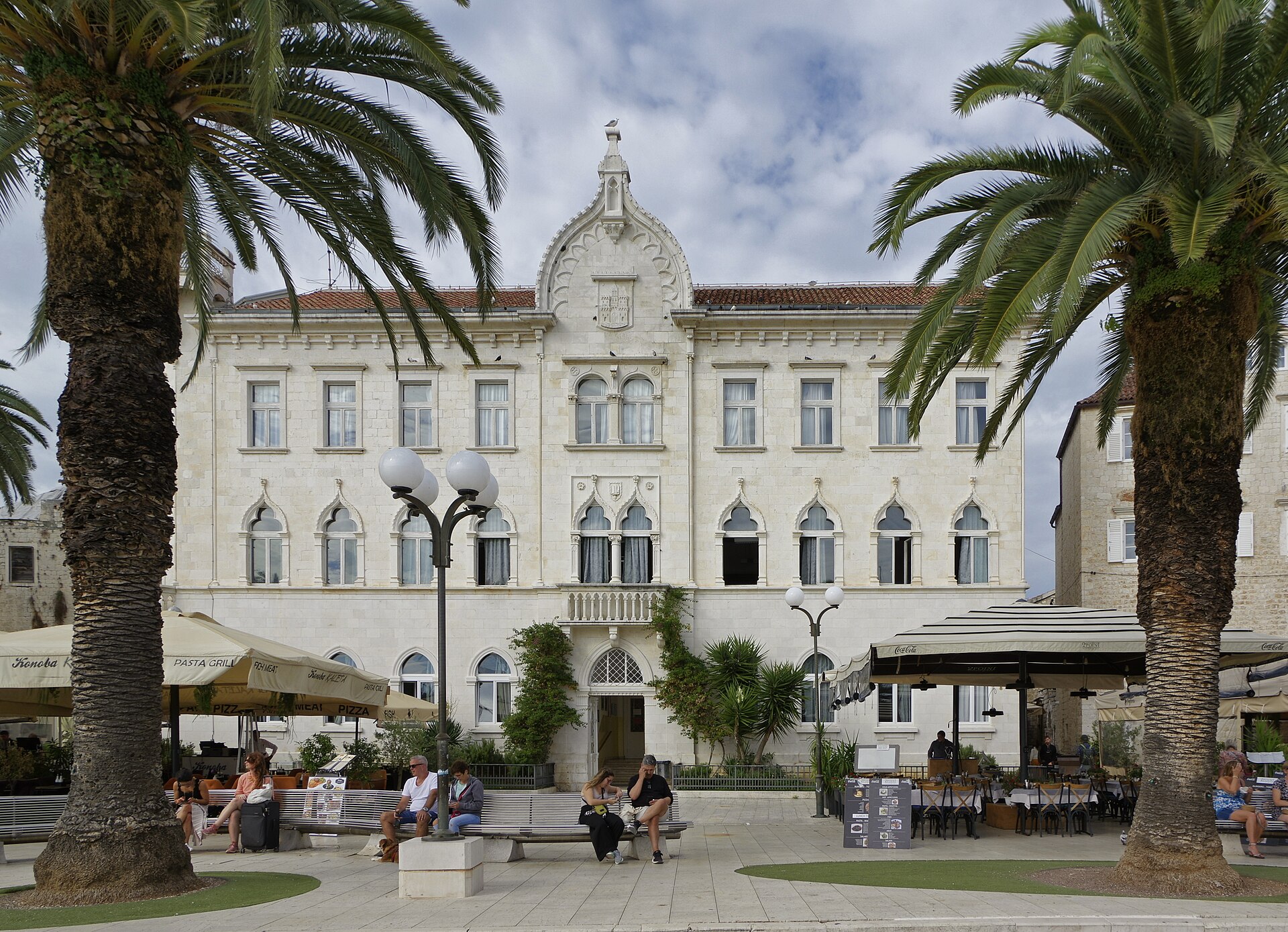 De boulevard aan het water van Trogir met palmen en terrassen